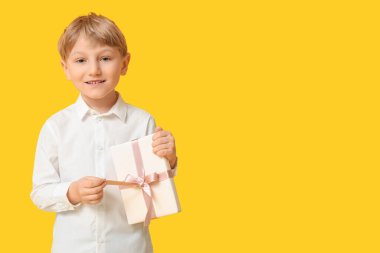 Sarı arka planda hediye kutusu olan şirin bir çocuk. Uluslararası Kadınlar Günü