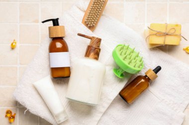 Silikon kafa masajı fırçası, bej kaplama arka planda kozmetik ürünler, sabun ve havlu.