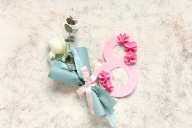 Hafif grunge arka planında figür 8 olan ambalaj kağıdına sarılı küçük bir buket bahar çiçeği. Uluslararası Kadınlar Günü