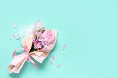 Turkuaz arka planda ambalaj kağıdına sarılmış bir demet güzel bahar çiçeği. Uluslararası Kadınlar Günü