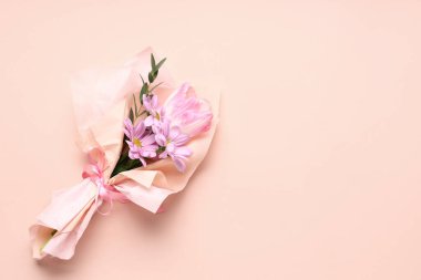 Pembe arka planda ambalaj kağıdına sarılmış küçük bir buket güzel bahar çiçeği. Uluslararası Kadınlar Günü