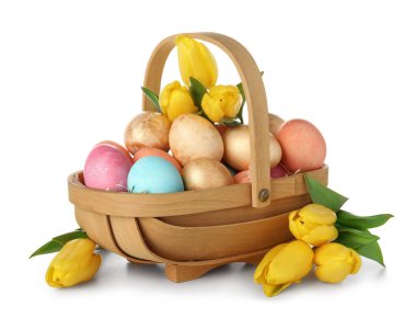Güzel Paskalya yumurtaları ve beyaz arka planda sarı laleler olan sepet.