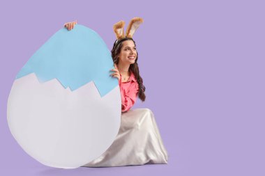 Büyük kâğıt kulaklı güzel bir kadın. Leylak arkaplanlı Paskalya yumurtası.