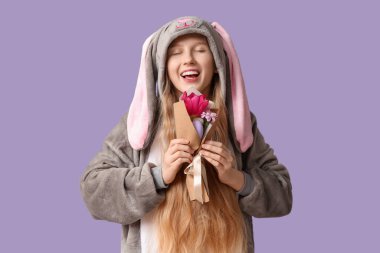 Mor arka planda çiçek ve yumurta demeti olan tavşan kostümlü güzel genç bir kadın. Paskalya kutlaması