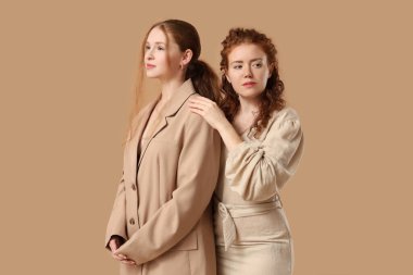 Kahverengi arka planda şık kızıl kız kardeşler