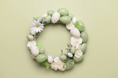 Beyaz çiçekli Paskalya çelengi, açık yeşil arka planda yumurta ve kelebekler.