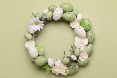 Beyaz çiçekli Paskalya çelengi, açık yeşil arka planda yumurta ve kelebekler.