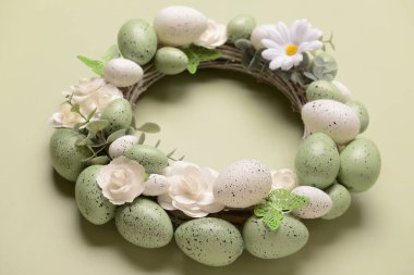 Beyaz çiçekli Paskalya çelengi, açık yeşil arka planda yumurta ve kelebekler.