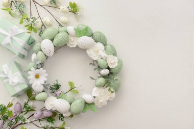 Beyaz çiçekli Paskalya çelengi, beyaz arka planda yumurtalar ve kelebekler