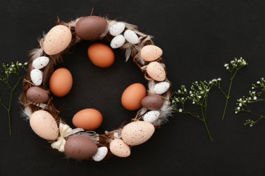 Siyah arka planda boyalı yumurta ve tüylü Paskalya çelengi