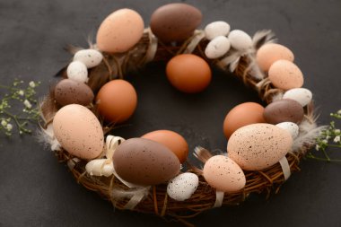 Siyah arka planda boyalı yumurta ve tüylü Paskalya çelengi