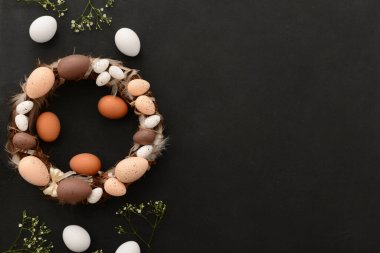 Siyah arka planda boyalı yumurta ve tüylü Paskalya çelengi