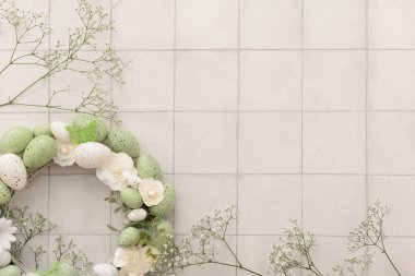 Paskalya çelengi, çiçeklerden, yumurtalardan ve kelebeklerden yapılmıştır. Beyaz fayansların üzerinde çingeneler serpiştirilmiştir.