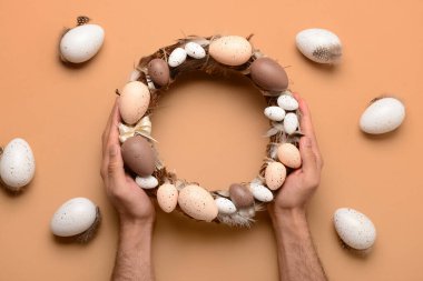 Erkek eller bej arka planda Paskalya çelengini tutuyor