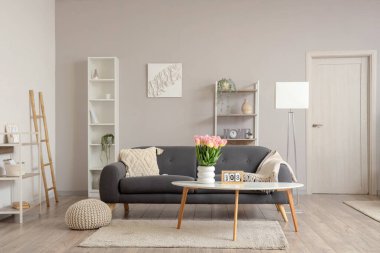 Uluslararası Kadınlar Günü için kanepe ve vazolarda lalelerle oturma odasının içinde.