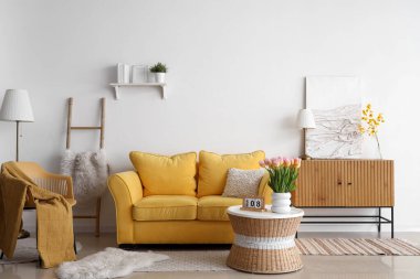 Uluslararası Kadınlar Günü için laleler ve kanepelerle aydınlık oturma odasının içinde.