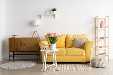 Uluslararası Kadınlar Günü için laleler ve kanepelerle aydınlık oturma odasının içinde.