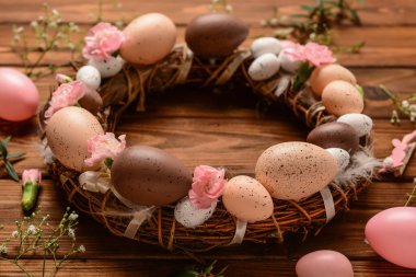 Tahta masada yumurta ve çiçeklerle süslenmiş Paskalya çelengi.