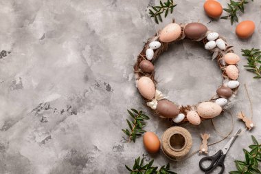 Paskalya çelengi, gri arka planda yumurta ve tüylerle süslenmiş. Üst görünüm