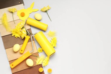 Boya ruloları, kumaş örnekleri, paskalya yumurtaları ve gri arka planda çiçekler.