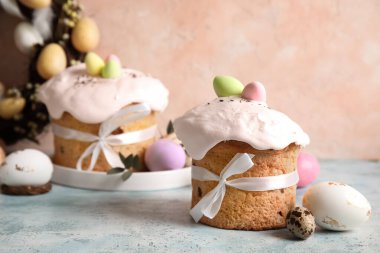 Lezzetli dekore edilmiş Paskalya pastaları ve renkli arka planda tabakta boyanmış yumurtalar.