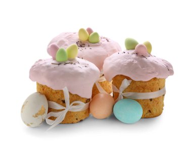 Lezzetli paskalya pastaları ve beyaz arka planda boyanmış yumurtalar.