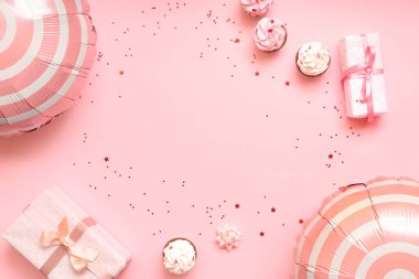 Hediye kutularıyla balonlar ve pembe arka planda kekler.