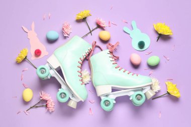 Paskalya yumurtaları, çiçekler ve mor arka planda kağıt tavşanlarla klasik patenler.