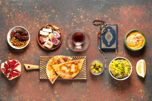 Traditional Eastern dishes, Turkish tea, Koran and prayer beads on grunge brown table. Ramadan celebration