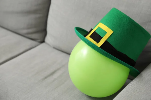 Green balloon with leprechaun\'s hat on grey sofa, closeup. St. Patrick\'s Day celebration