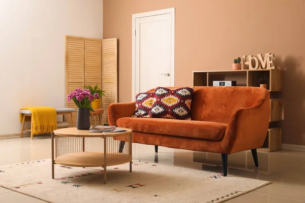 Stylish living room with brown sofa and bouquet of beautiful tulips on coffee table