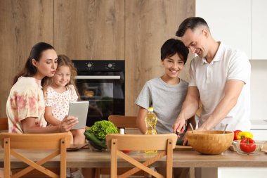 Anne babası mutfakta yemek pişiren küçük çocuklar.