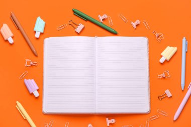 Turuncu arka planda okul kırtasiyesi olan boş bir defter