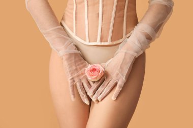 Bej arka planda gülü olan genç bir kadın, yakın plan. Seks konsepti