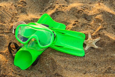 Yeni yüzme maskesi, deniz yıldızı ve kumda yüzgeçler.