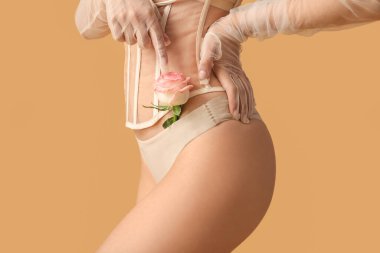 Bej arka planda gülü olan genç bir kadın, yakın plan. Seks konsepti