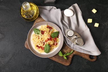 Lezzetli makarna tabağı ve siyah arka planda malzemeler.