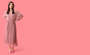 Pembe arka planda şık giyinmiş, metin için yeri olan güzel bir genç kadın.