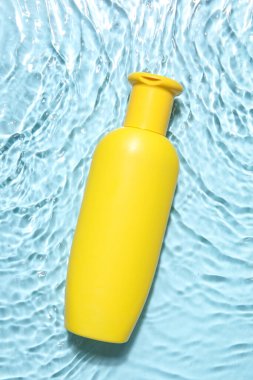 Renkli suda bir şişe güneş kremi.