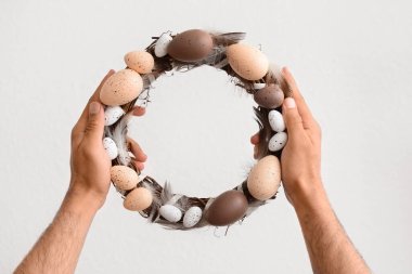 Beyaz arkaplanda Paskalya çelengi tutan adam