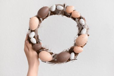 Beyaz arka planda Paskalya çelengi tutan kadın.