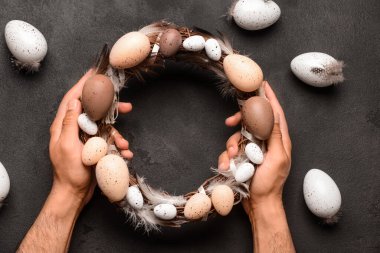 Paskalya çelengini siyah grunge masasında tutan adam.