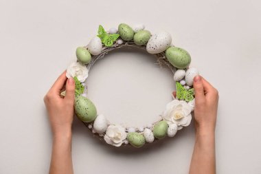 Beyaz masada Paskalya çelengi tutan kadın.