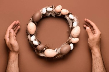 Kahverengi masada bitirilmiş Paskalya çelengini gösteren bir adam