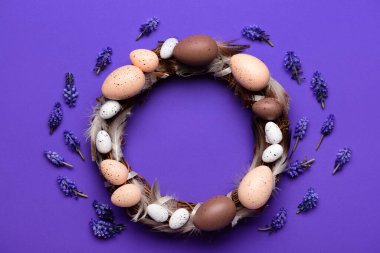 Koyu mor arka planda yumurta ve tüylü Paskalya çelengi