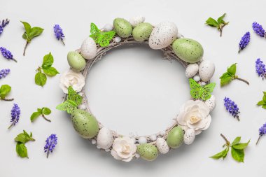 Beyaz arka planda çiçekli, yumurtalı ve kelebekli Paskalya çelengi