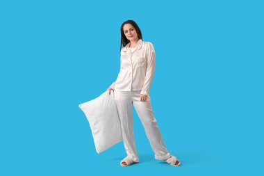 Mavi arka planda yumuşak yastıklı güzel bir kadın.