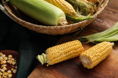 Tahta ve hasır sepette tahtadan yapılmış taze mısır koçanları var.