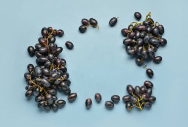 Mavi arka planda tatlı siyah üzümlerden yapılmış çerçeve