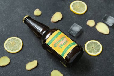 Siyah zemin üzerinde taze zencefilli bira, limon dilimleri ve buz küpleri olan kompozisyon, yakın plan.
